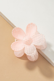 Up close photo of Light pink checkered patterned daisy hair claw clip on a white and tan background 