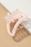 Semi transparent light pink colored crescent shaped hair claw with a light pink polkadot pattern.  Hair claw has 2 flowers at the top of the crescent hair claw.