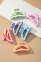 Multiple matte pastel colored crescent shaped hair claw clips arranged in a tan and white background. Colors of hair claws include: light green, pink, lavender, light blue, light orange, and coral