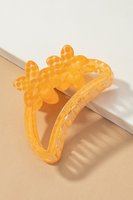 Semi transparent orange with a polkadot pattern crescent shaped hair claw.  Hair claw has 2 flowers at the top of the crescent hair claw.