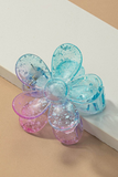 Blue and pink clear gradient clear speckled patterned daisy hair claw clip on a white and tan background 