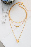 two necklaces, one gold and the other one silver. Both necklaces feature three chains graduating in length. The shortest chain is a textured chocker length chain, the second chain has 5 gold beads in the center, the third chain has a triangle charm. 
