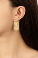 Upclose picture of a curve bar earring with gold tassels behind the earlobe