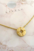 Up close photo of a delicate gold necklace with dainty gold compass charm. Necklace is photographed on a jewelry card