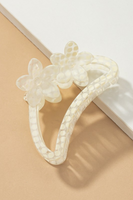 Semi transparent white colored crescent shaped hair claw with a white polkadot pattern.  Hair claw has 2 flowers at the top of the crescent hair claw.