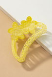 Semi transparent yellow colored crescent shaped hair claw with a yellow polkadot pattern.  Hair claw has 2 flowers at the top of the crescent hair claw.