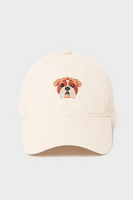cream colored baseball style cap with an embroidered/needlepoint style bulldog face in the center of the cap 
