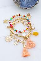 3 piece gold bracelet set laying on top of each other on top of a white background. Bracelets include: a multi color beaded elastic bracelet with dangling charms, another bracelet includes a gold beaded elastic bracelet with a blush colored tassel charm, the third bracelet is a gold rectangle link bracelet with a toggle closure, bracelet also has a blush tassel charm, a gold coin charm, a pearl charm, a yellow stone charm, a white and gold daisy charm and a simple beige bead.